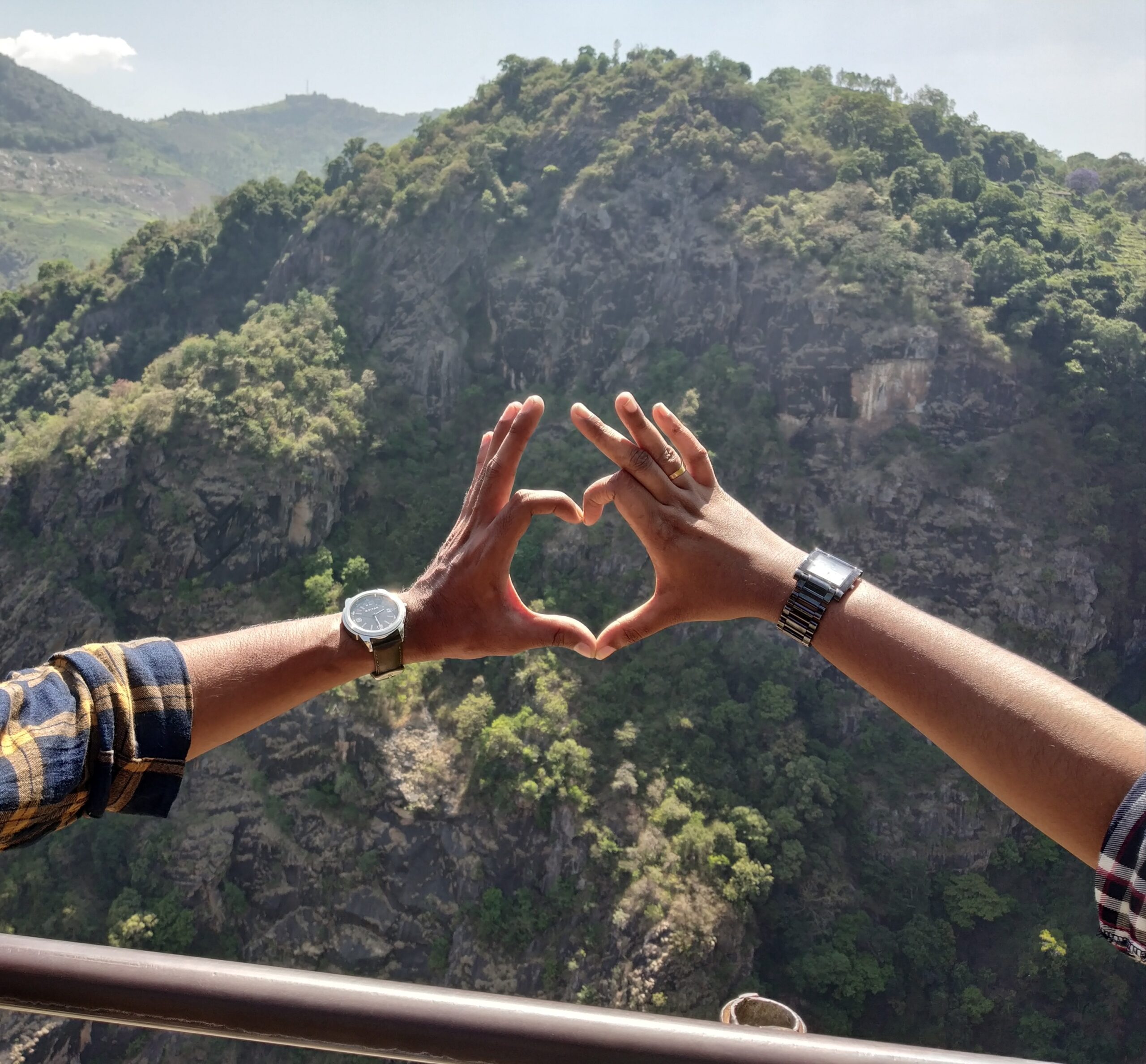 two person forming heart shape by hands